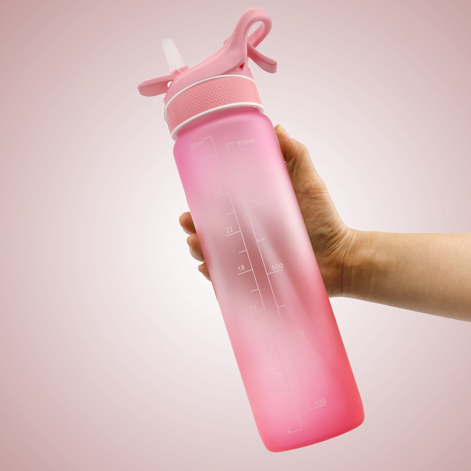 Hand håller i en rosa och röd  Vattenflaska med sprej 1000 ml