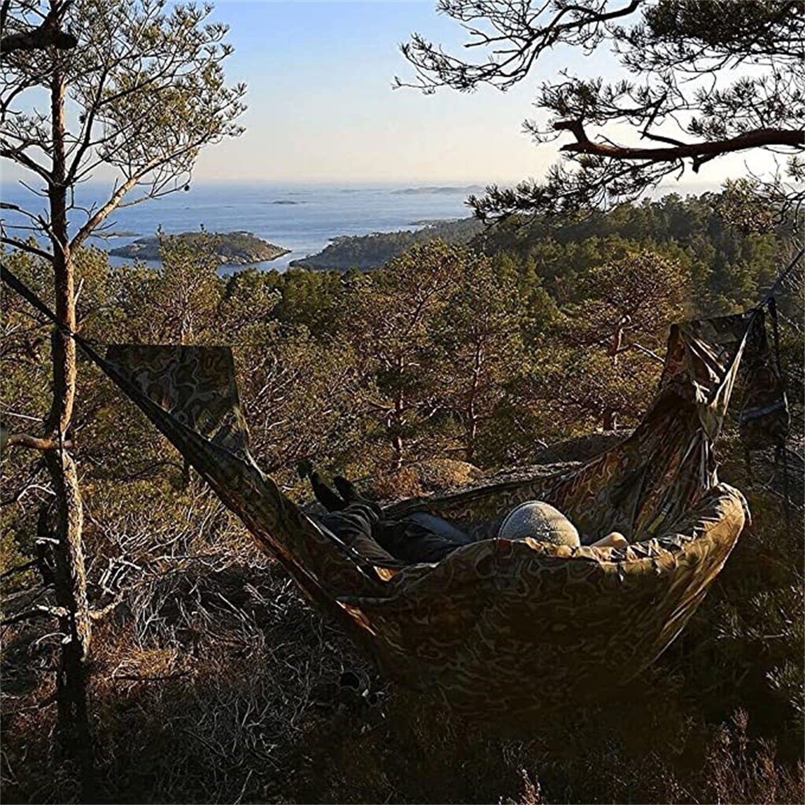 en kamofärgad hängmatta på en topp med utsikt över havet