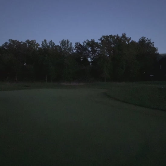 En person slår till en golfboll som börjar lysa upp på en golf green