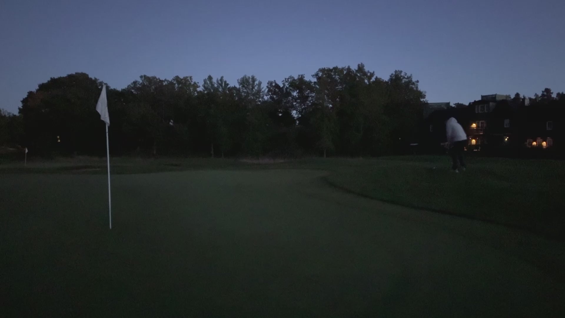 En person slår till en golfboll som börjar lysa upp på en golf green